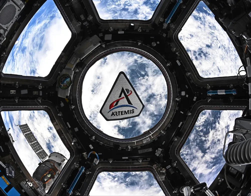 空间站 Cupola 舷窗中的地球与 Artemis 标志